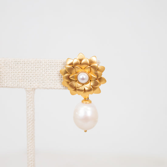 Gold earring with pearl on a light gray background