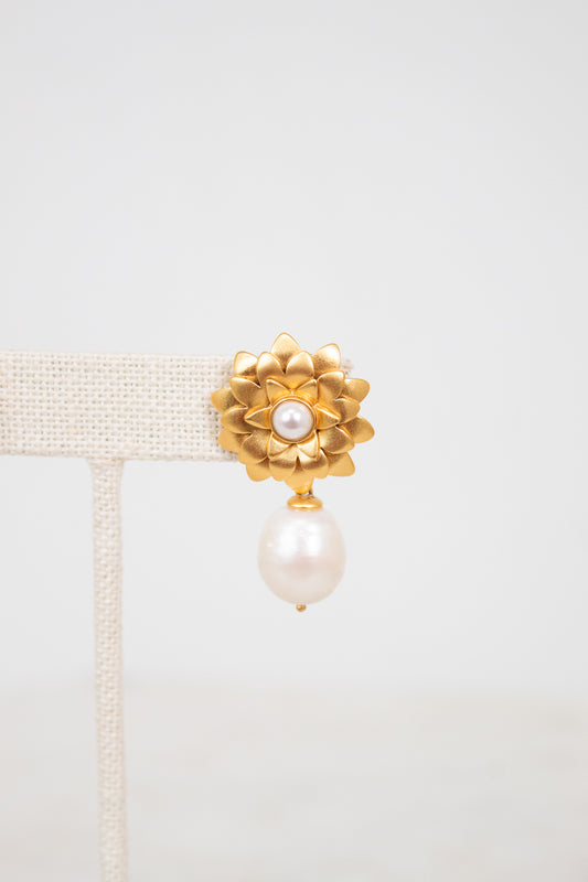 Gold earring with pearl on a light gray background