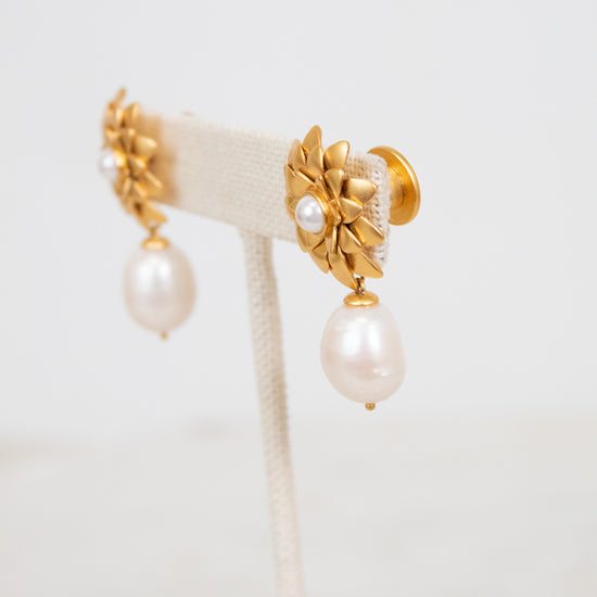 Gold earrings with pearl drops on a white background
