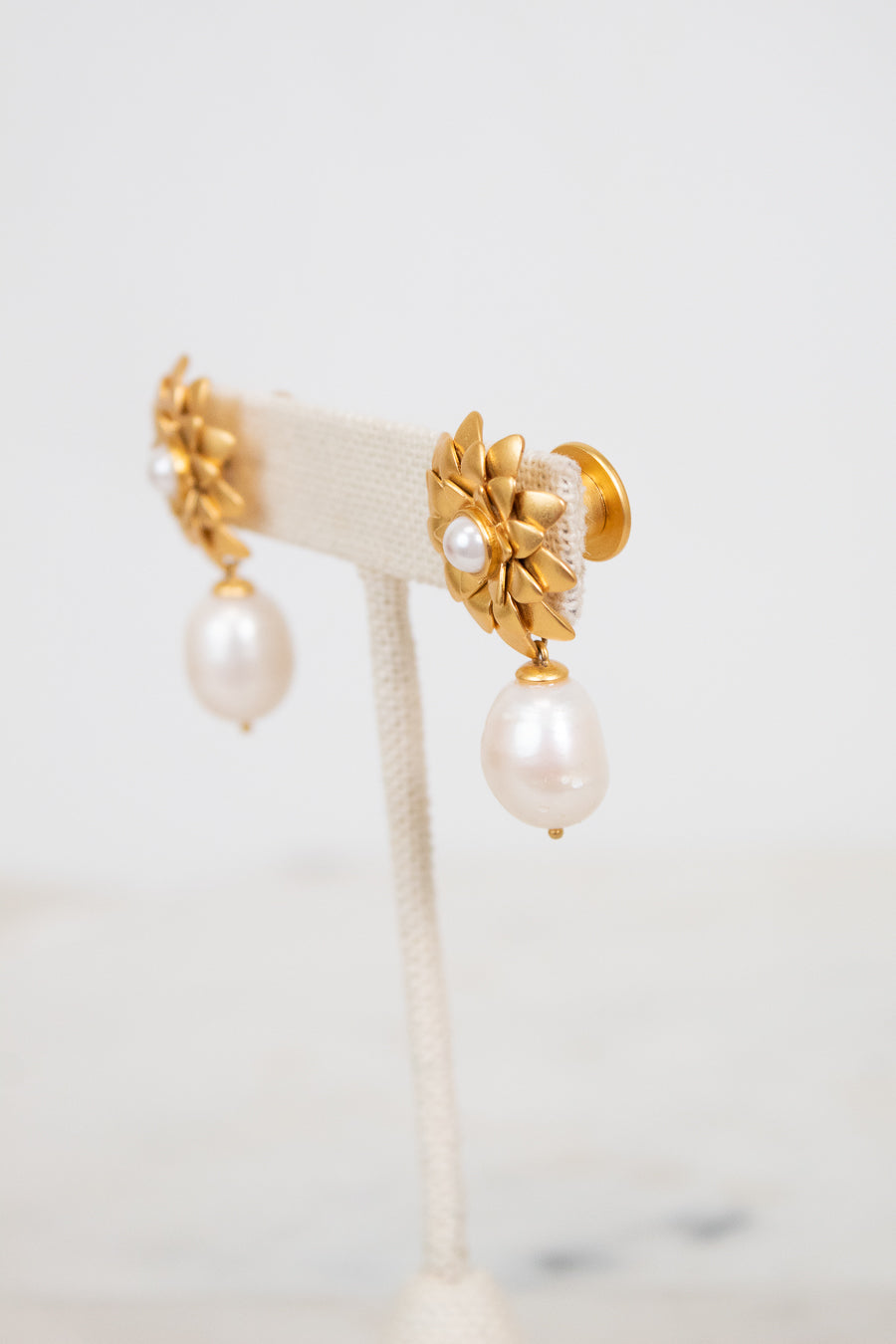 Gold earrings with pearl drops on a white background