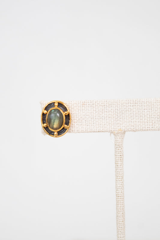 Jewelry display with a ring featuring a green stone on a white background