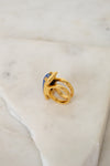 Gold ring with a blue gemstone on a marble surface