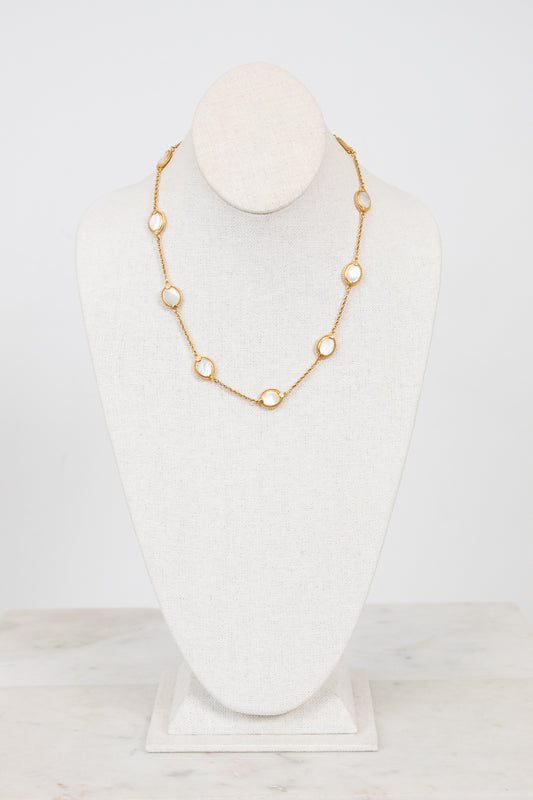 Gold necklace on a white mannequin bust against a white background