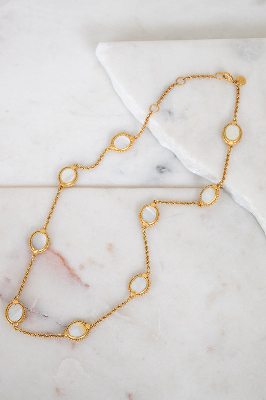 Gold necklace with circular pendants on a marble surface