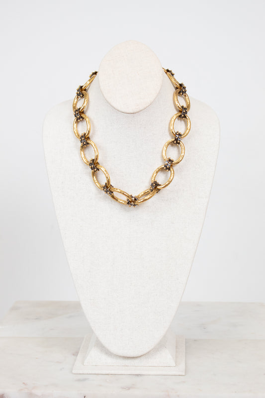 Gold chain necklace on a white mannequin bust against a white background