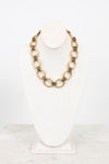 Gold chain necklace on a white bust with a white background