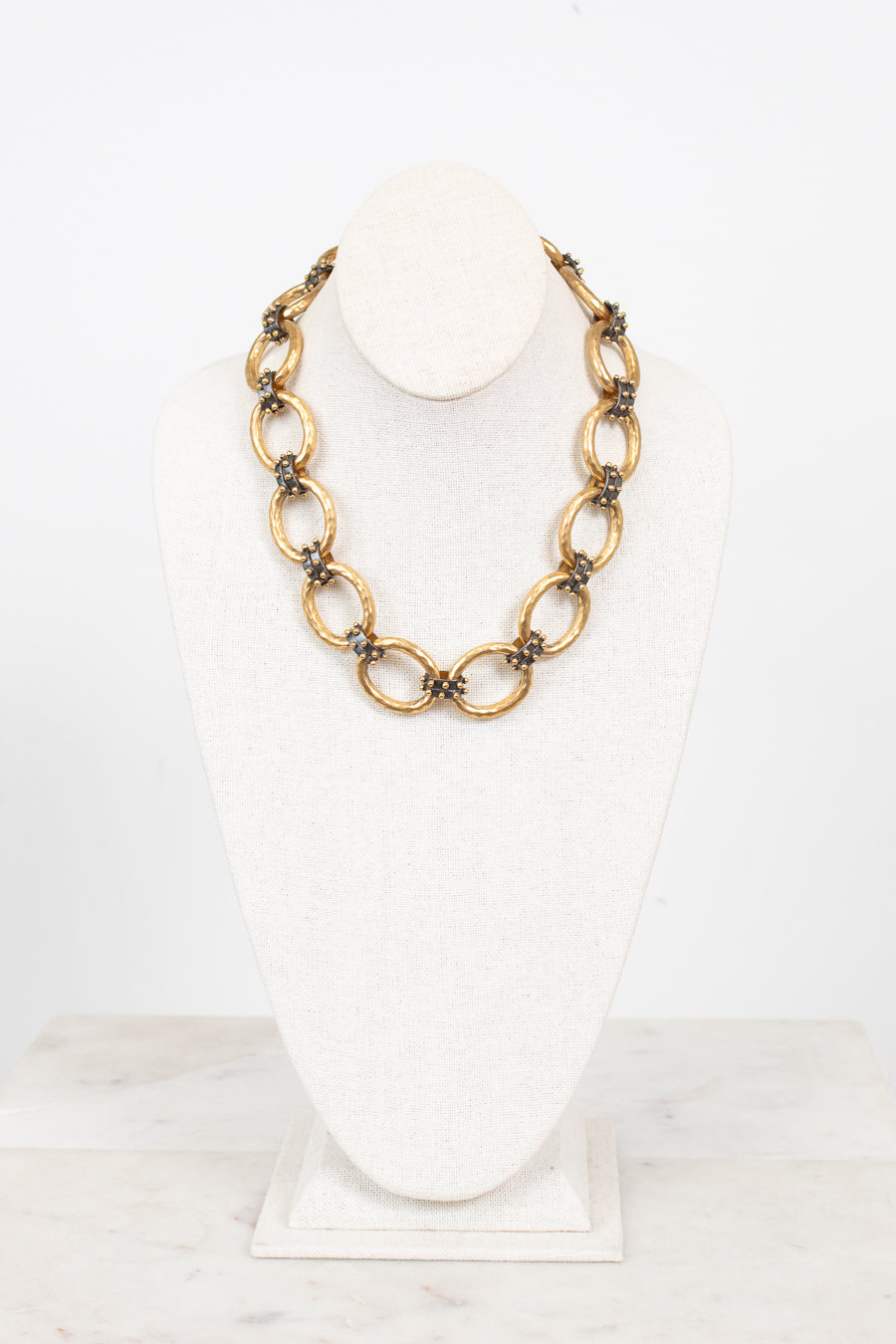 Gold chain necklace on a white bust with a white background