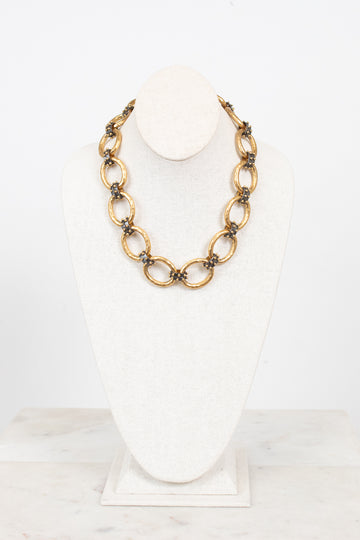 Gold chain necklace on a white bust with a white background
