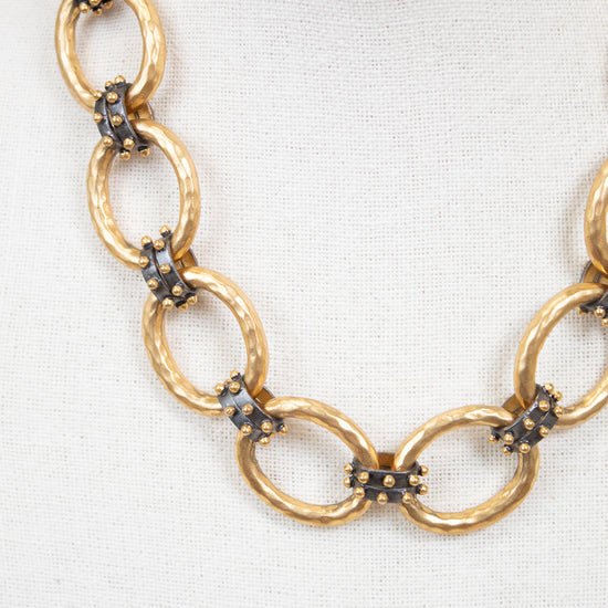 Gold chain necklace with embedded stud details on a white background