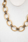 Gold chain necklace with embedded stud details on a white background