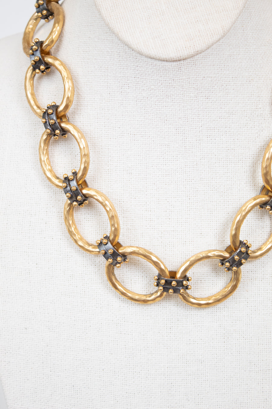 Gold chain necklace with embedded stud details on a white background