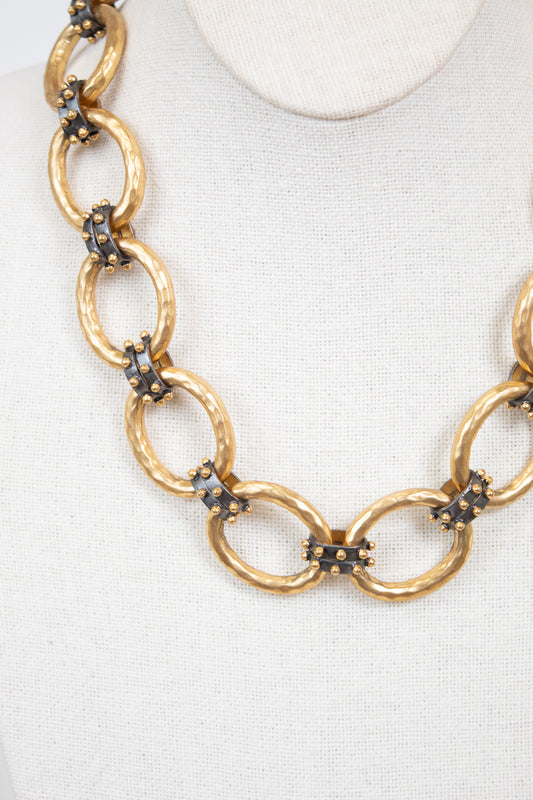 Gold chain necklace with embedded stud details on a white background