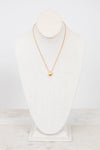 Gold necklace on a white mannequin bust against a white background