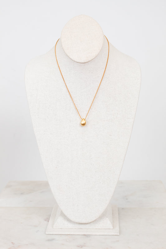 Gold necklace on a white mannequin bust against a white background