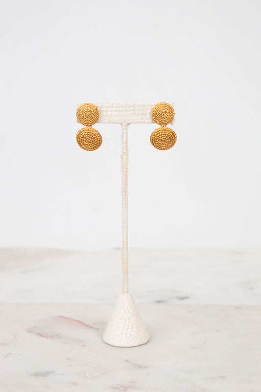 Gold circular earrings on a white stand with a white background