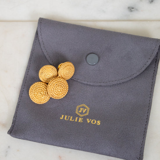 Gray pouch with gold coins and 'Julie Vos' branding on a marble surface