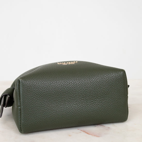 Base of green leather bag on a light marble surface