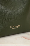 Green leather handbag with 'kate spade New York' logo on a marble surface