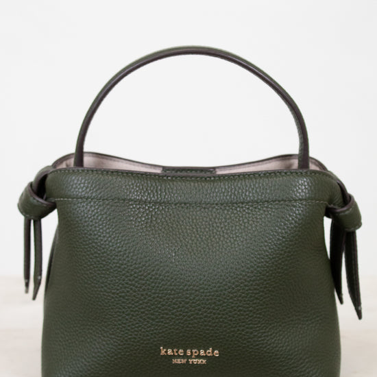 Green handbag with 'kate spade new york' logo on a white background