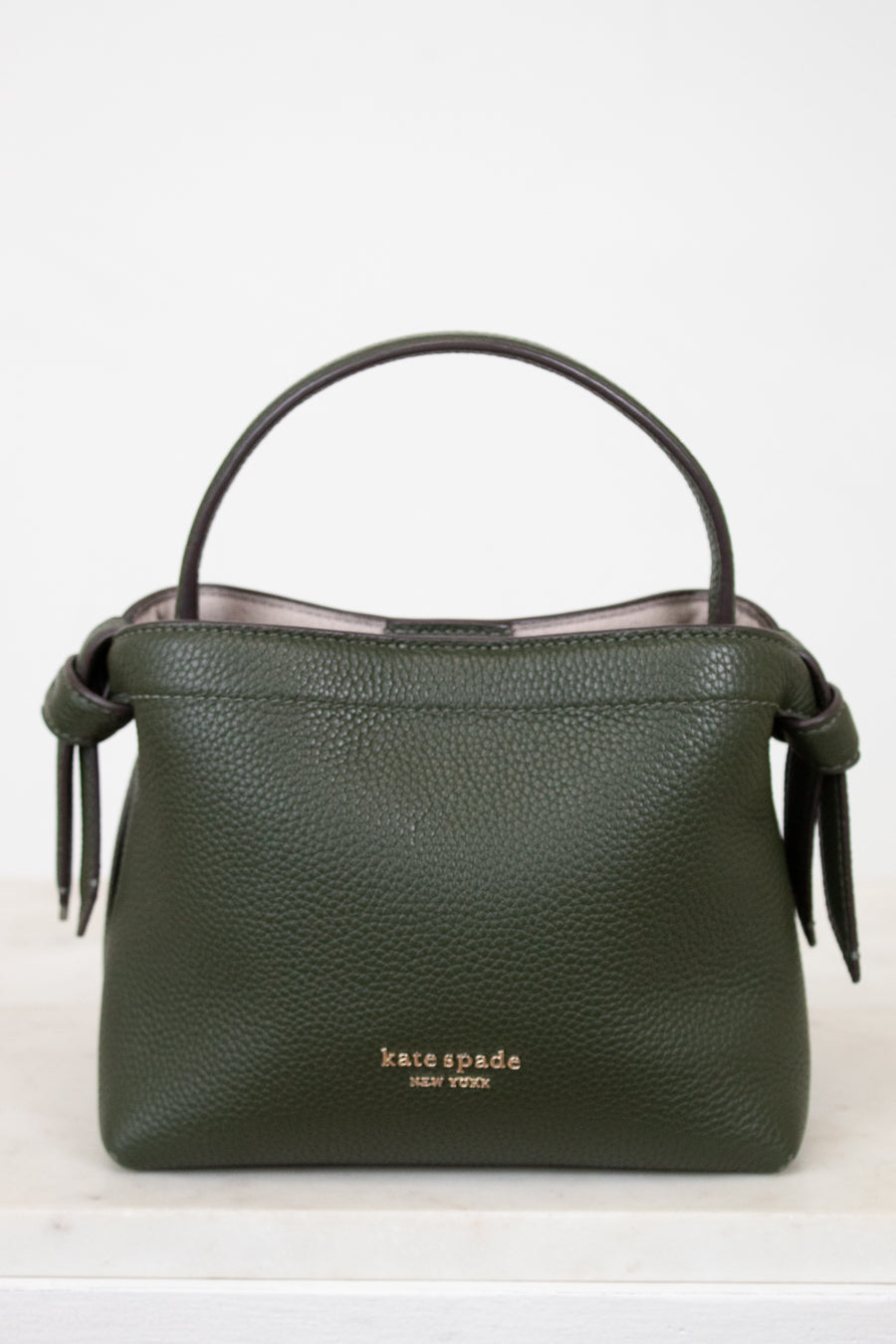 Green handbag with 'kate spade new york' logo on a white background