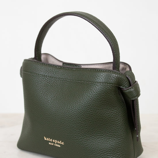 Green handbag with 'kate spade new york' logo on a white background