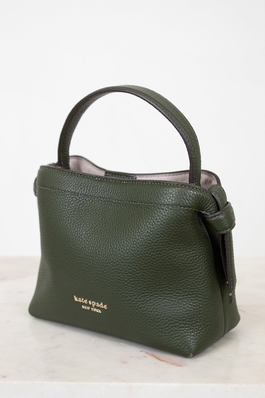 Green handbag with 'kate spade new york' logo on a white background