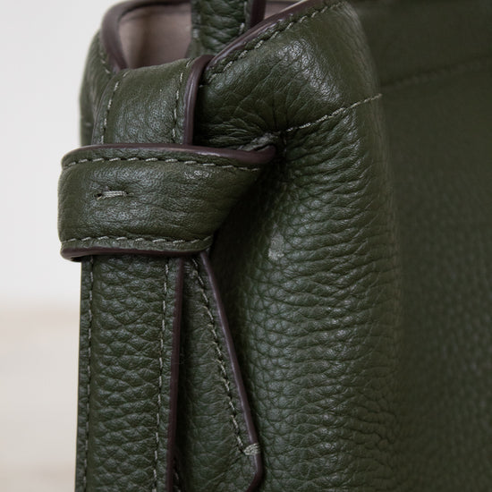Close-up of a green leather handbag with a knot detail.