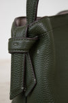 Close-up of a green leather handbag with a knot detail.