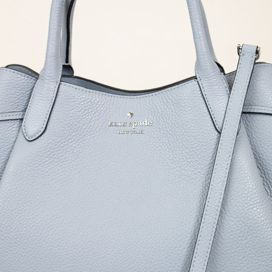 Light blue handbag with a visible brand logo on a beige background