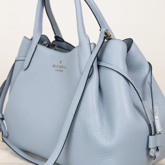 Light blue handbag with a visible brand logo on a light background
