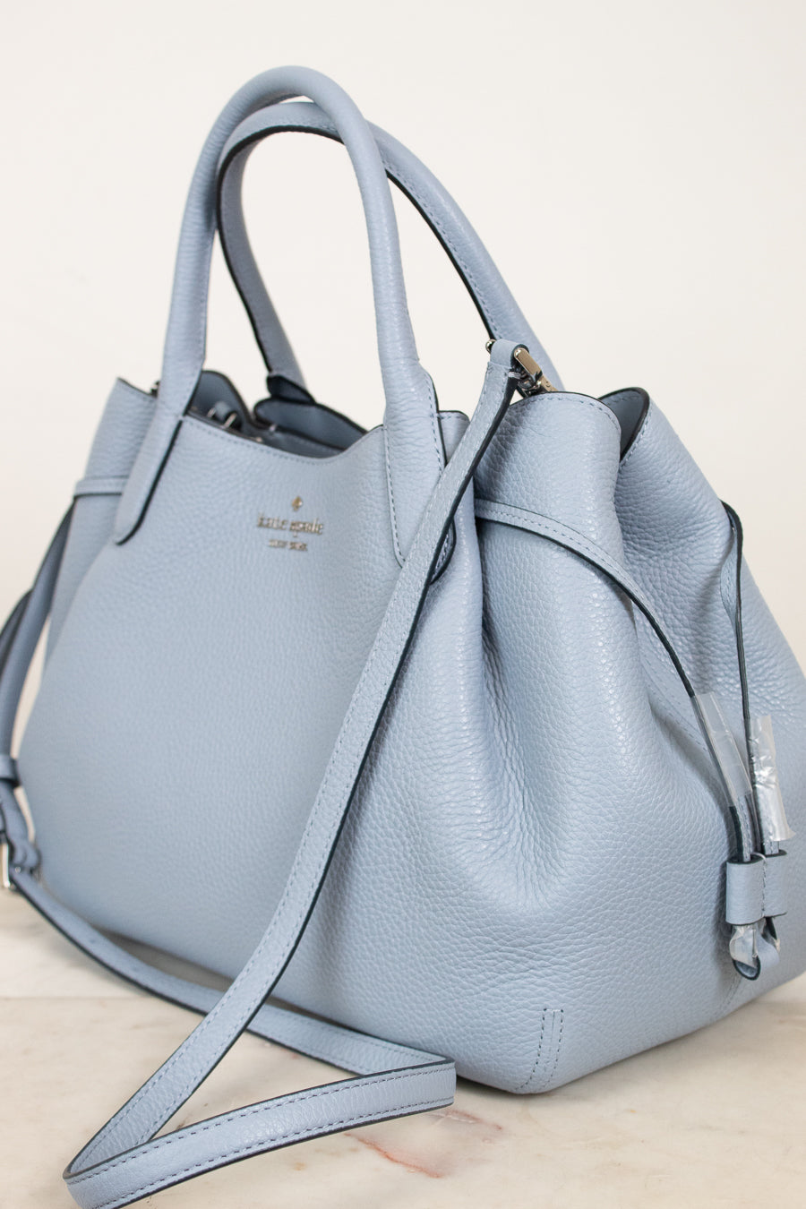 Light blue handbag with a visible brand logo on a light background
