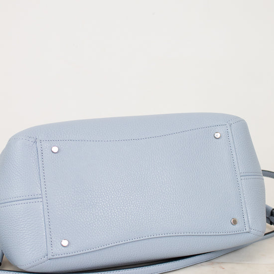 Light blue handbag with silver studs on a light marble surface