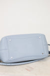 Light blue handbag with silver studs on a light marble surface