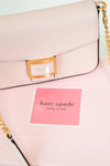 Pink handbag with gold chain detail and 'kate spade New York' label.