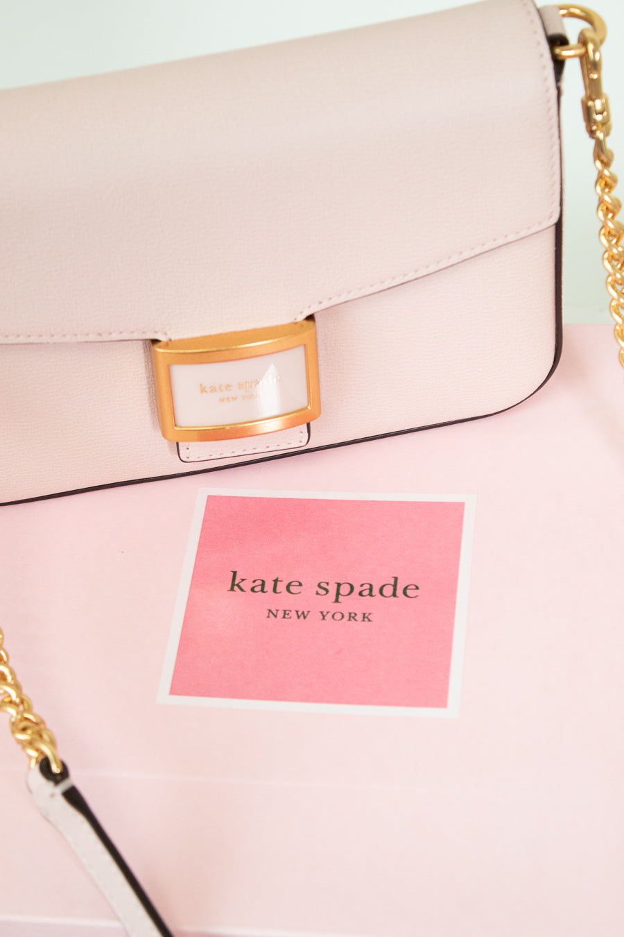 Pink handbag with gold chain detail and 'kate spade New York' label.