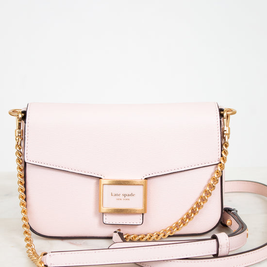 Pink handbag with gold chain strap on a light background