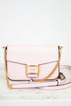Pink handbag with gold chain strap on a light background
