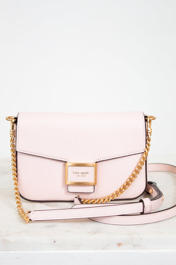 Pink handbag with gold chain strap on a light background