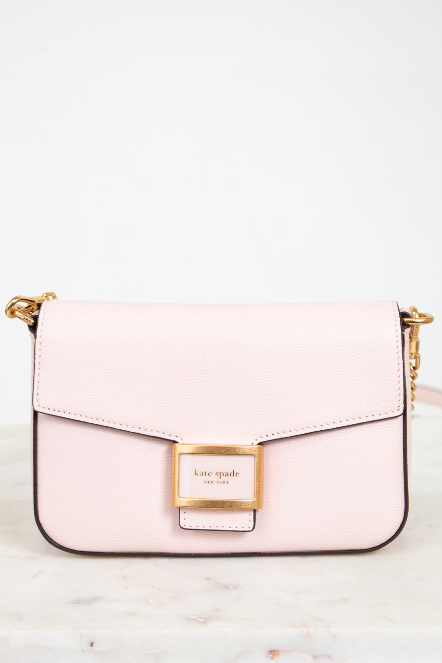 Pink handbag with gold accents on a white background