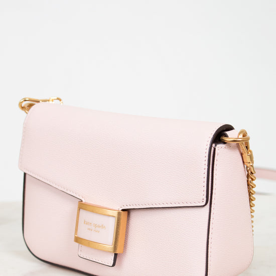 Pink handbag with gold accents on a light background