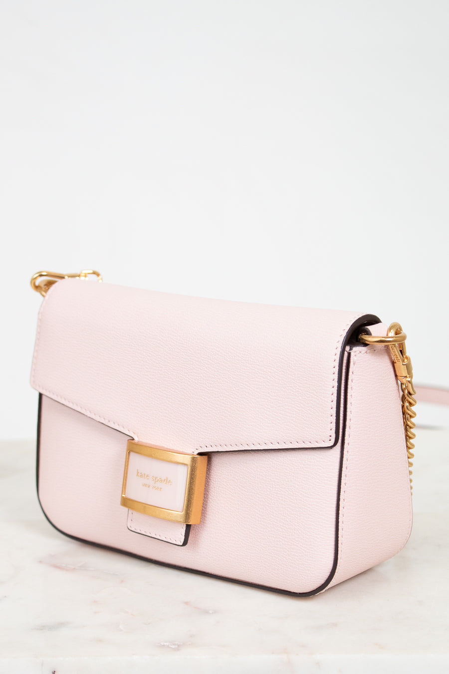 Pink handbag with gold accents on a light background