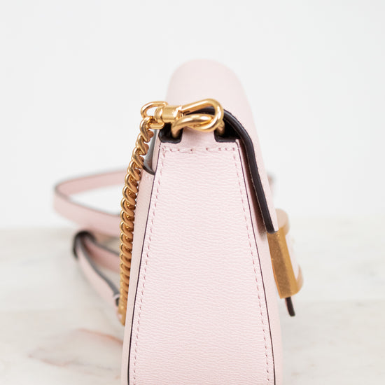 Pink handbag with gold chain detail on a white background