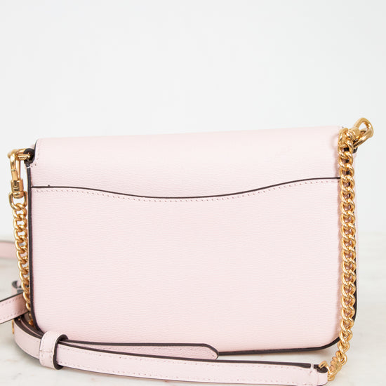 Pink handbag with gold chain strap on a white background
