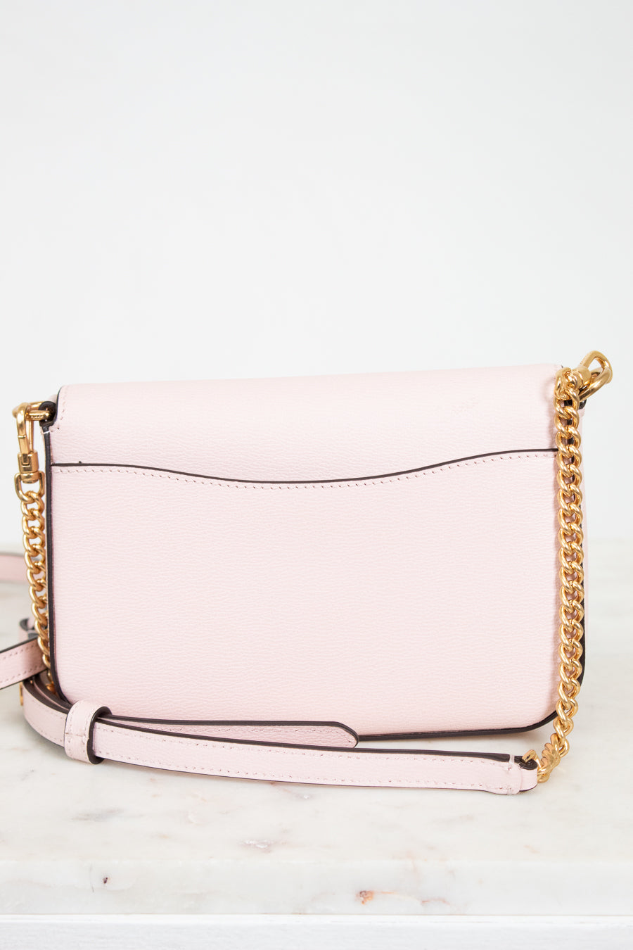 Pink handbag with gold chain strap on a white background