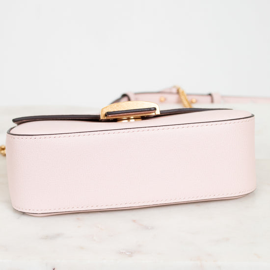 White handbag with gold clasp on a light marble surface