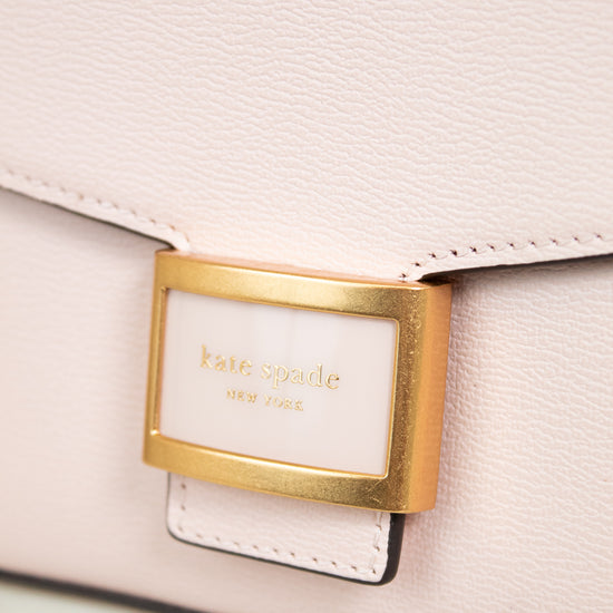 Close-up of a light pink handbag with a gold clasp and 'kate spade' label.