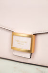 Close-up of a light pink handbag with a gold clasp and 'kate spade' label.