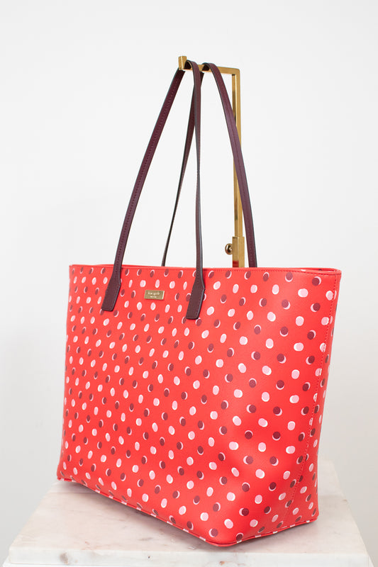 Red polka dot tote bag with brown handles on a white background