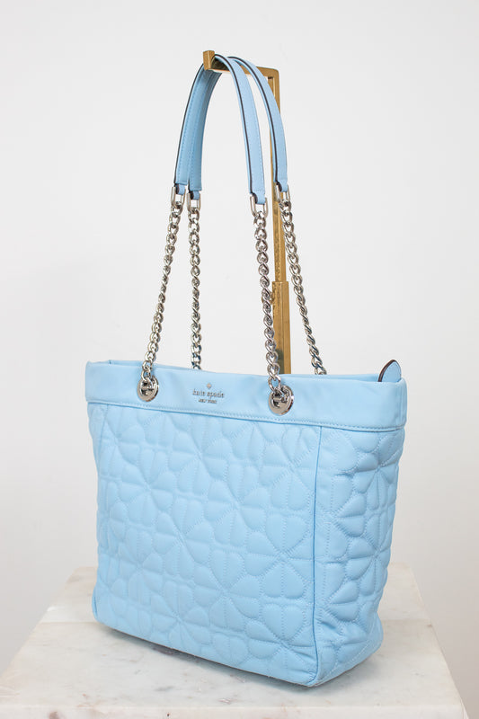 Light blue quilted handbag with chain detail on a white background