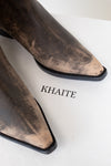 Brown pointed-toe boots with 'KHAITE' branding on a white background